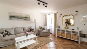 Un salon comprenant un canapé, un fauteuil, une table basse et une console sur laquelle sont posés des paniers.