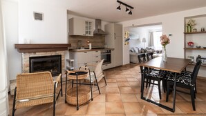 Une cuisine avec une cheminée, une table à manger, des chaises et un îlot central.
