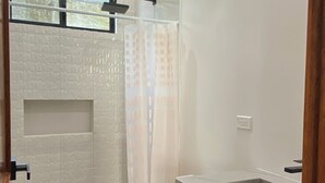 A modern bathroom with a white toilet, a shower with a glass door, and a black cabinet.