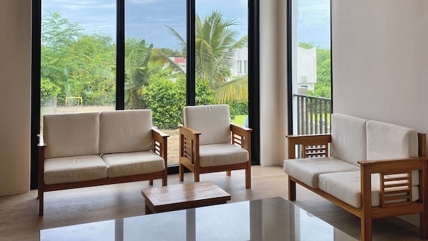 A spacious living area with a large glass door leading to a balcony, wooden furniture, and a reflective floor.