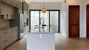 A modern kitchen with a central island, built-in appliances, and a large window.