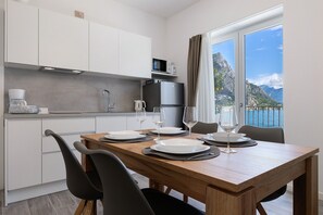 Een moderne keuken met witte kastjes, een magnetron en een koelkast. Er staat een eettafel gedekt met borden, glazen en een koffiezetapparaat.