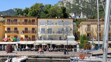 Un edificio frente al agua con balcones, asientos exteriores y un puerto deportivo con barcos.