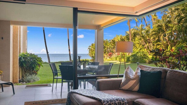 Un salon moderne avec une porte vitrée donnant sur un balcon qui offre une vue sur l’océan.