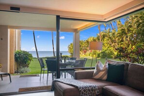 Een moderne woonkamer met een glazen deur die leidt naar een balkon met uitzicht op de oceaan.