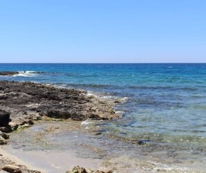 A rocky shoreline with clear water and a clear sky. - La Dolce Vita with a Sea View (Torre Suda)