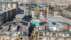 A modern hotel complex with multiple buildings, solar panels on the roofs, and a mountainous backdrop.