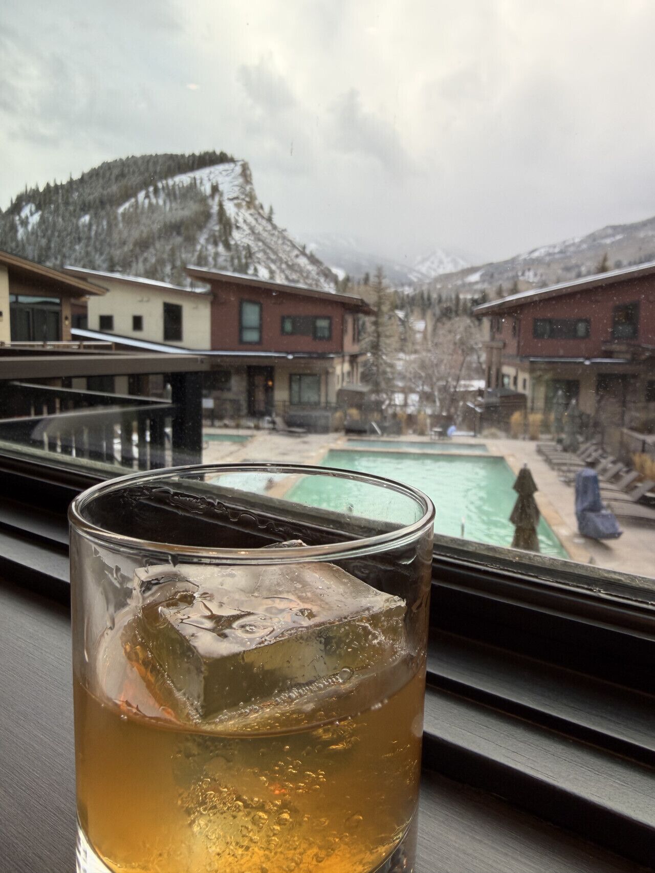 A glass of iced tea with a mountain view through a window.
