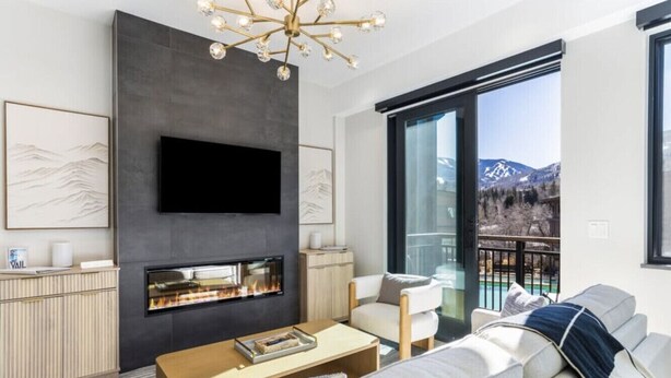 A modern living room with a flat-screen TV, fireplace, and a sofa.