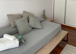 A neatly made bed with grey bedding, a small statue, and a rolled white towel. - G Nova in Javea X bia (Javea)