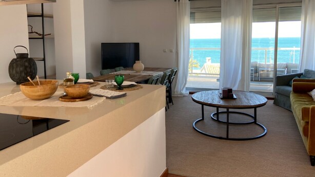 Ein modernes Wohnzimmer mit Küchenzeile, einem Esstisch und Blick auf den Ozean.