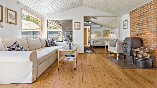 A spacious living area with a high ceiling, wooden flooring, a white sofa, a coffee table, and a fireplace. - 4 bedroom stunning home in Gilleleje (Gilleleje)