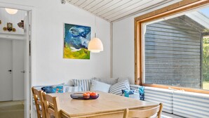 A dining area with a wooden table and chairs, a bowl of fruit, and a painting on the wall. - 4 bedroom stunning home in Gilleleje (Gilleleje)
