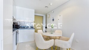 Une cuisine moderne avec des meubles blancs, une table à manger avec quatre chaises et un petit îlot central.