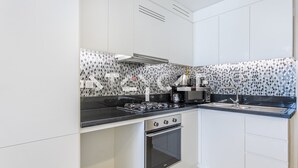Une cuisine de taille réduite équipée d’une cuisinière à gaz, d’un four et d’une machine à café.