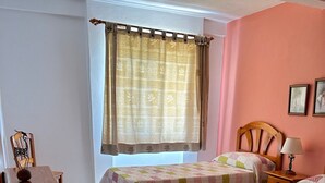 A room with two beds, a wooden chair, a small table, and a window with curtains. - Apartment 'Apartamento 4' with Shared Pool, Private Terrace, and Wi-Fi (Los Llanos)
