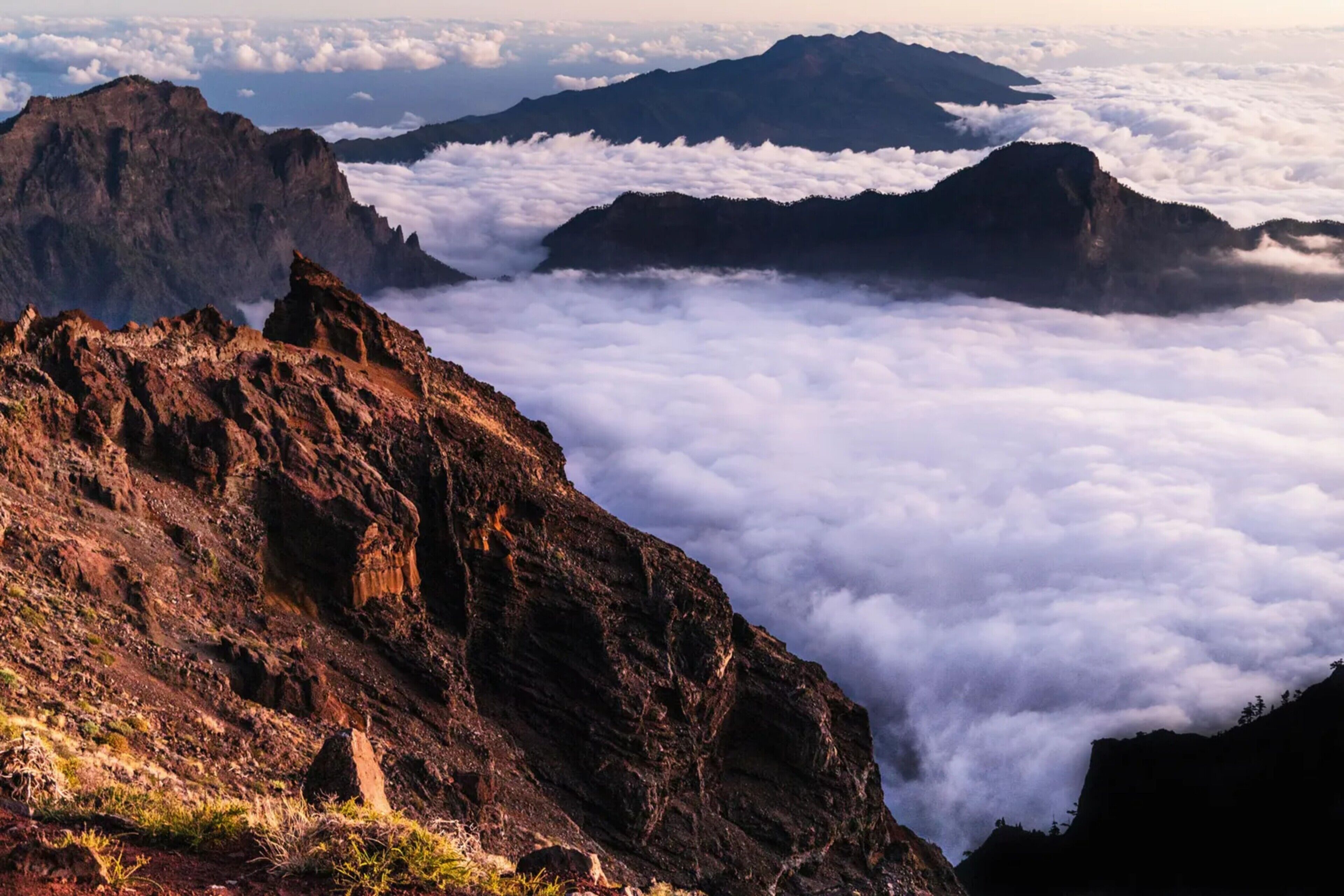 Paisaje montañoso con terreno rocoso y vistas a valles cubiertos de nubes.