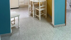 Une cuisine compacte avec des meubles blancs, une table à manger et un petit comptoir pour prendre le petit-déjeuner.