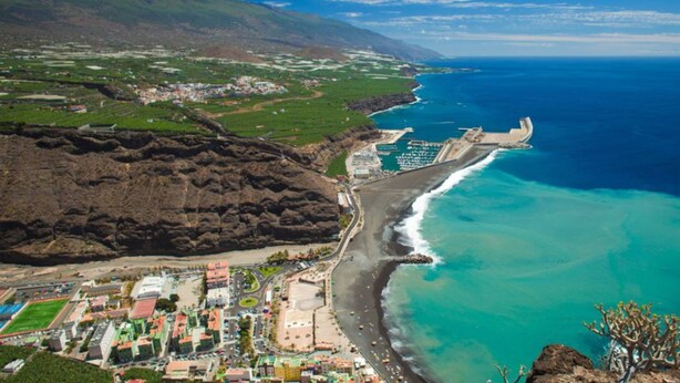 Une ville côtière dotée d’une plage, d’un barrage et bordée de montagnes.