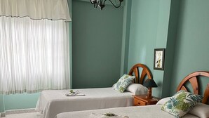 A room with two beds, a chandelier, a window with curtains, and a framed picture on the wall. - Apartment for 5 with private terrace, shared pool & Wi-Fi in Los Llanos (Los Llanos)