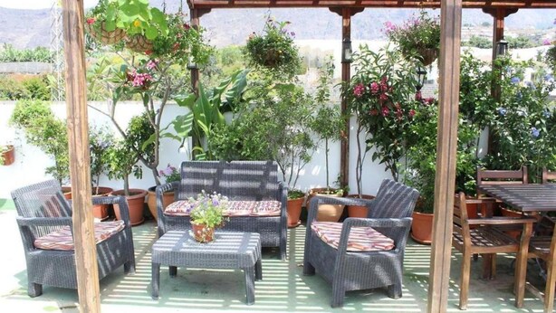 An outdoor patio with wicker furniture, potted plants, and a pergola structure. - Apartment for 5 with private terrace, shared pool & Wi-Fi in Los Llanos (Los Llanos)
