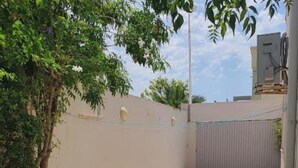 A courtyard with a paved area, a tree, and a hose on the ground. - Villa sérénité, Yasmine hamamet (Yasmine Hammamet)