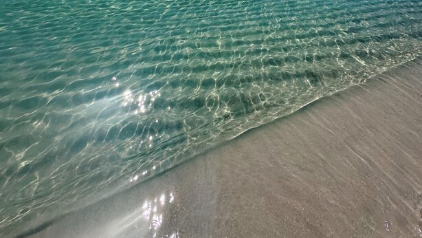 A beach with clear water and a visible light beam from the sun. - New, update, waterfront condo. Relaxing water sounds and view. (Pensacola Beach)