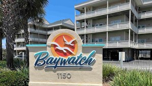 A sign for Baywatch at 1150, featuring a stylized bird logo. - New, update, waterfront condo. Relaxing water sounds and view. (Pensacola Beach)
