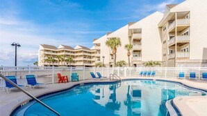 A swimming pool with lounge chairs and a white fence. - New, update, waterfront condo. Relaxing water sounds and view. (Pensacola Beach)