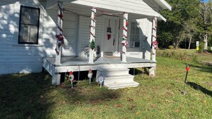 A white house with a porch decorated with Christmas garlands and ornaments.