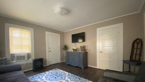 A living room with a sofa, a patterned rug, a television, and a cabinet.