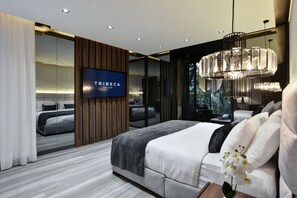 A modern bedroom with a large bed, a TV mounted on the wall, and a view of the outdoors through a glass door. - Luxury 4BR Villa with Rooftop and Jacuzzis on Lleras Park (Medellín)