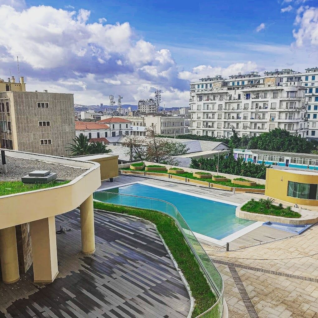 A rooftop pool area with a clear view of surrounding buildings and a cityscape in the background.