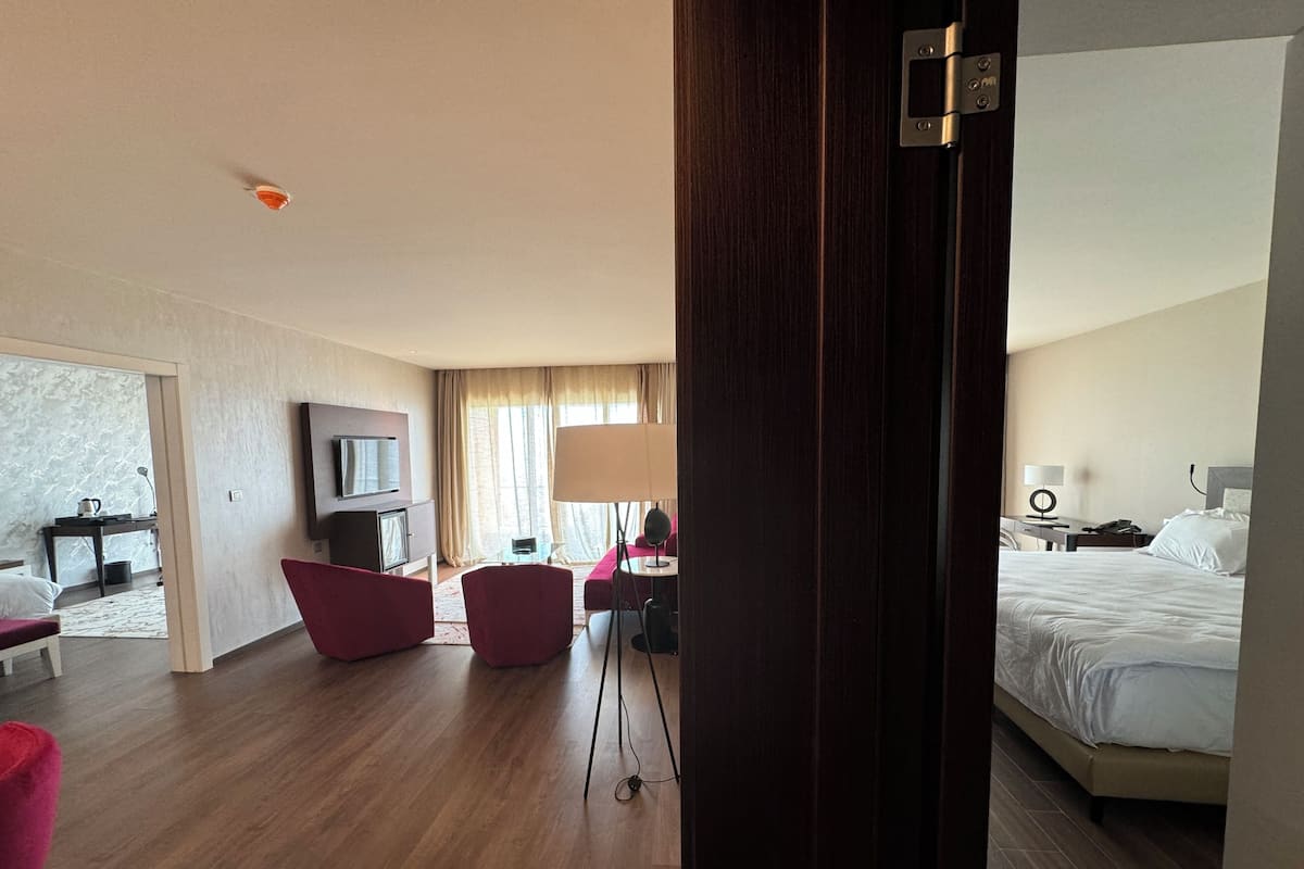 A hotel room with a bed, a desk, a chair, a TV, and a window with curtains.