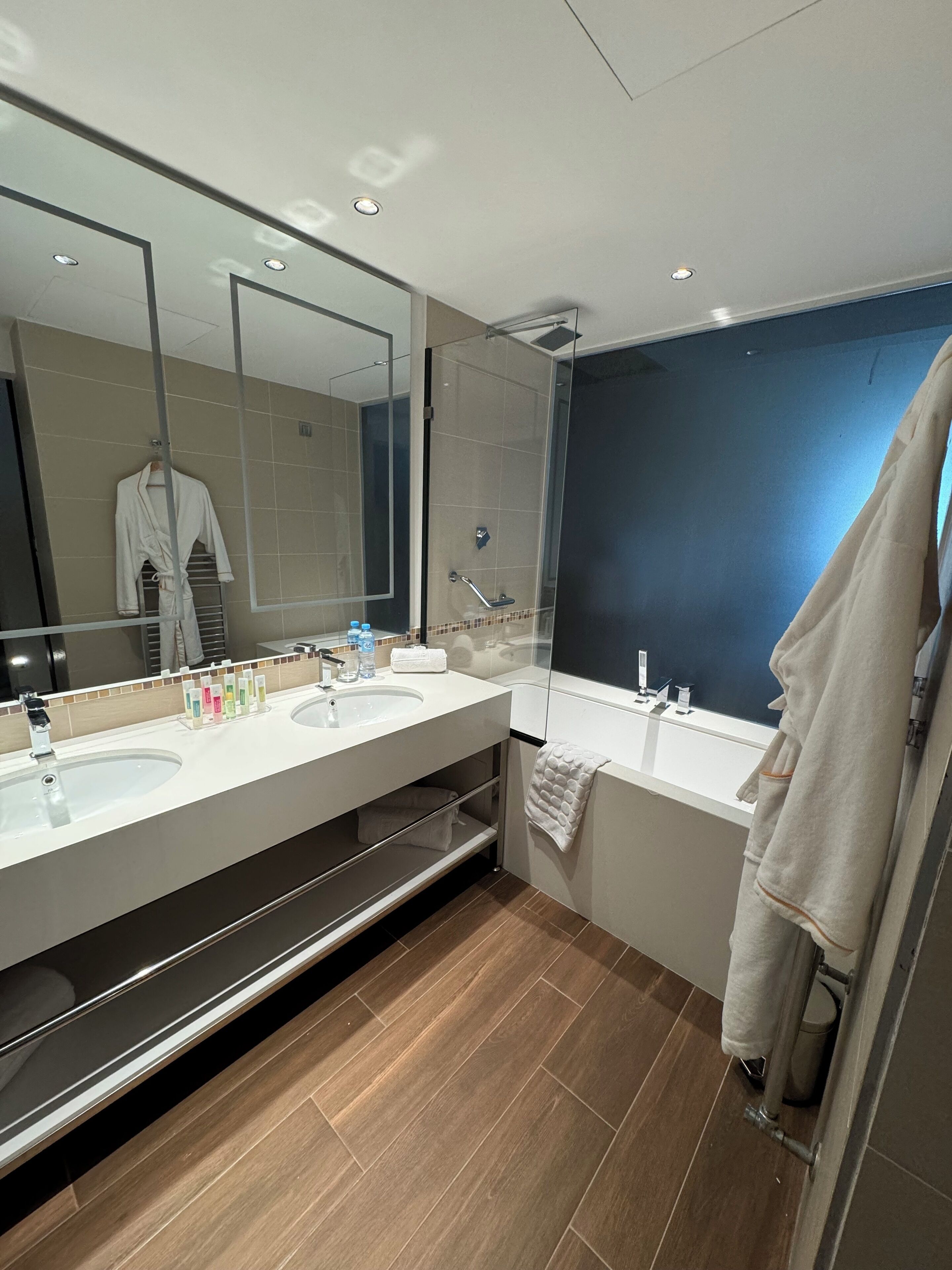 A modern bathroom with two sinks, a large mirror, and a shower.