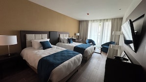 A hotel room with two beds, a desk, a chair, a TV, and a window with curtains. - Seybouse Hotel & SPA (Annaba)