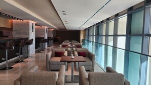 A modern restaurant with high tables and cushioned seating, marble columns, and large windows. - Seybouse Hotel & SPA (Annaba)