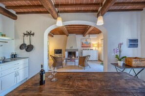 A kitchen with a wooden table, two chairs, a bottle, and two glasses.