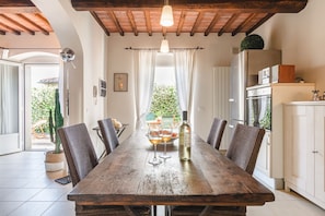 Un coin repas rustique avec une table en bois, des chaises en osier et une bouteille de vin.