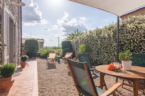Eine Terrasse mit Sitzgelegenheiten im Freien, einem runden Tisch und Topfpflanzen.