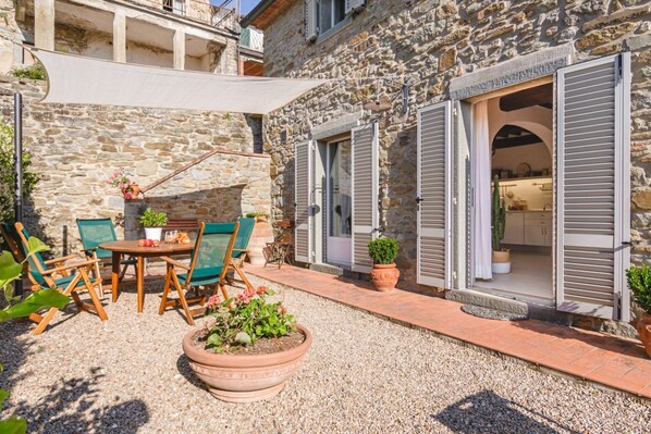 A stone building with a patio area, outdoor seating, and a small garden.