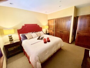 A hotel room with a large bed, two bedside tables, a wardrobe, and a door. - Soaring Eagle 301 Ski In Out! (Snowshoe)