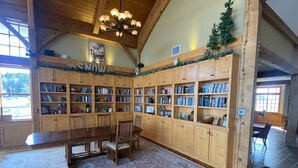 Une bibliothèque spacieuse avec des étagères en bois, une grande table en bois et un tapis à motifs.