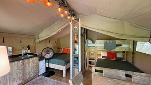 Une tente compacte et bien éclairée, équipée d’un coin cuisine, de deux lits et d’une petite table.