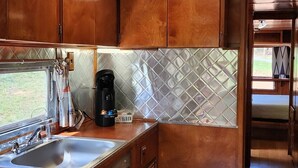 A compact kitchen with wooden cabinets, a stainless steel sink, and a tiled backsplash. - Vintage 1955 Imperial Mansion, deck on the creek, easy access to pool and playground, sleeps 5. (Mill Spring)