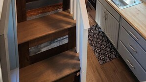L’intérieur d’une cabine comprend un escalier en bois, un lit superposé, un coin cuisine et une petite salle de bain.