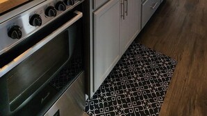 Une cuisine moderne dotée d’appareils électroménagers en acier inoxydable, de meubles blancs et d’un plan de travail en bois.