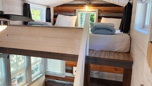 Une petite cabine comprenant un lit en mezzanine, un canapé et un escalier.