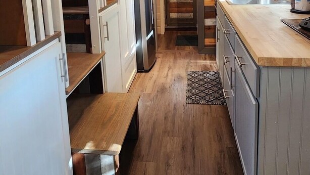 Une cuisine moderne avec un plancher en bois, une cuisinière encastrée et un grand îlot central doté d’un évier.