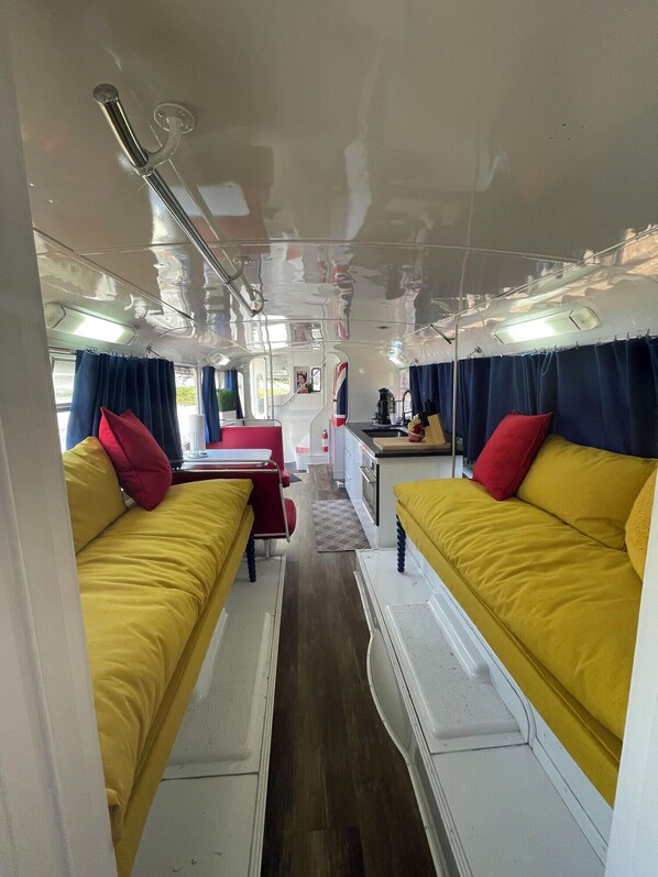 A compact interior with two yellow sofas, a small kitchenette, and a dining area.